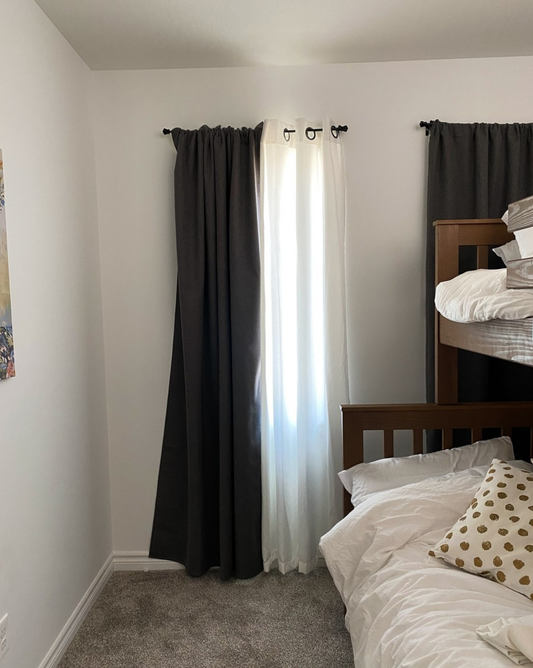 Insulated blackout curtain blocking light beside regular curtain