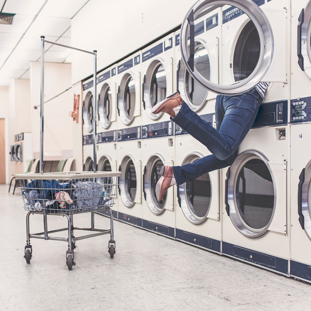 A picture of a person stuck in a laundry machine because they don't know how to wash blackout curtains