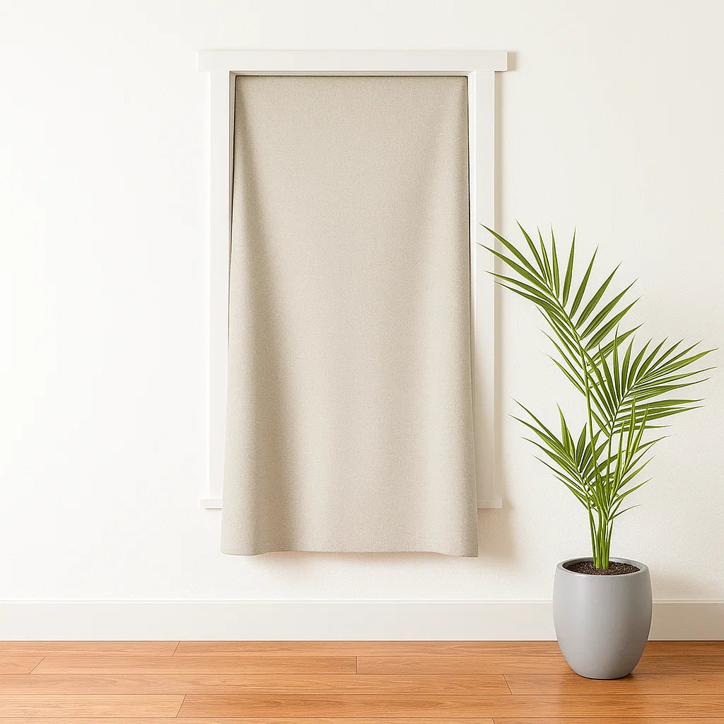 A beige portable blackout curtain installed on a wall, next to a potted plant on the floor.